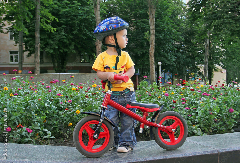 Small white boy in a protective helmet and jeans standing on the Small white boy in a protective helmet and jeans standing on the