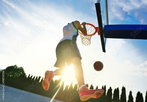 Street basketball player performing power slum dunk.