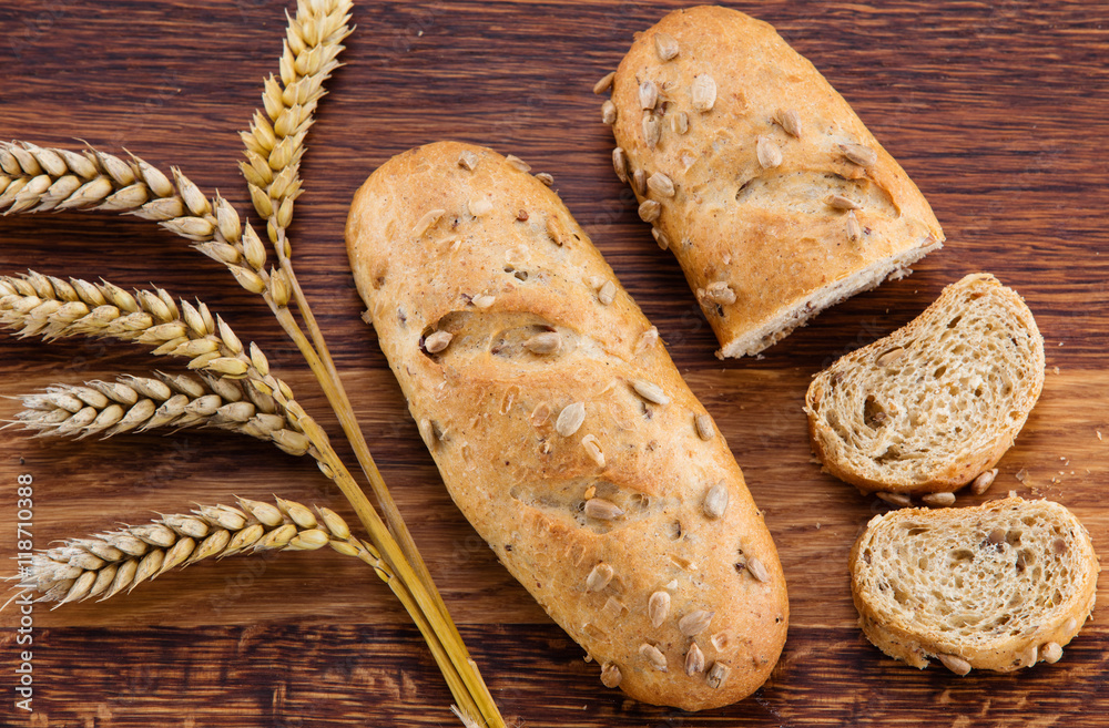 Loaf of bread, bread slices and wheat over wooden background Loaf of bread, bread slices and wheat over wooden background