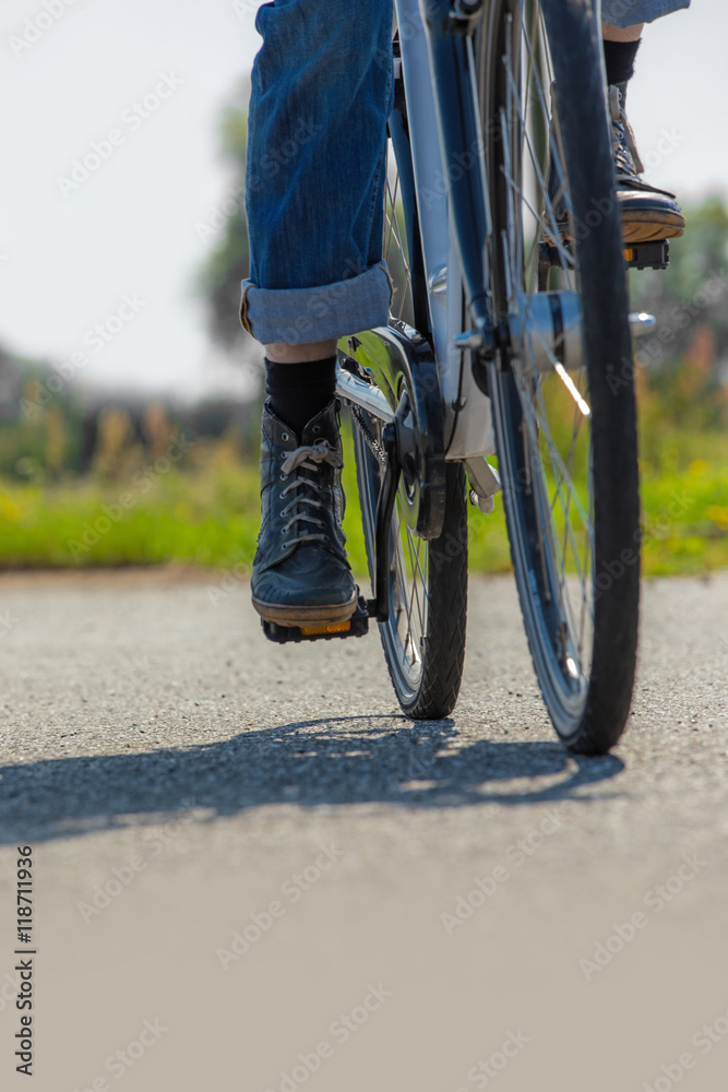 Fototapeta premium Eine Frau fährt mit dem Fahrrad auf einer Asphaltstrasse entlang