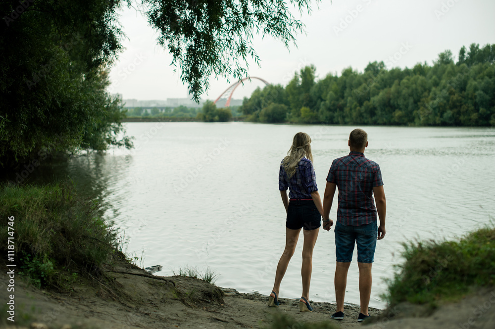 enamored guy and girl spend time walking on the bank of the river on boats background