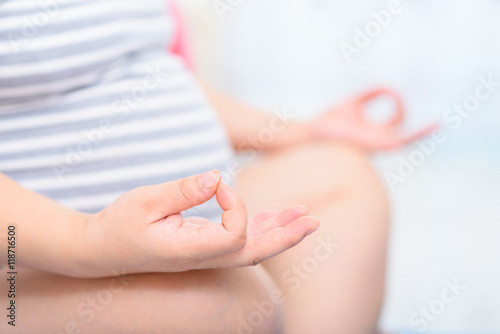 Closeup of pregnant woman sitting in a lotus position.