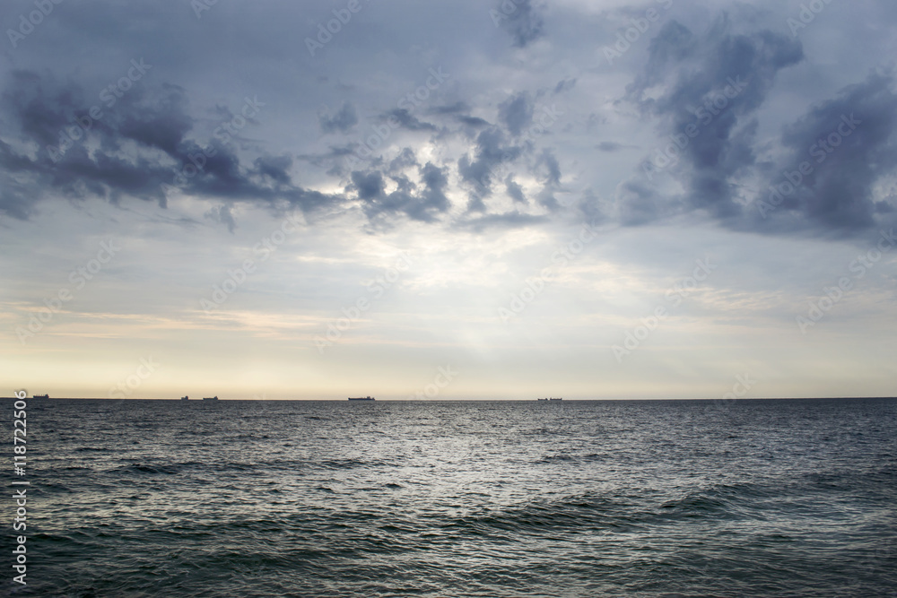 Seascape with ships on the horizon and cloudy sky