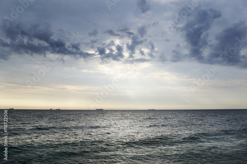 Seascape with ships on the horizon and cloudy sky