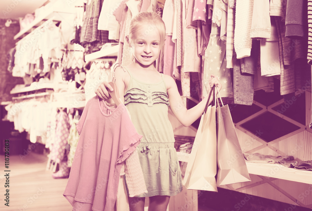 portrait of  girl standing in kids clothes store with shopping b