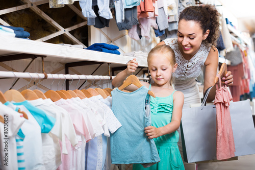 young mother with daughter buying kids clothes
