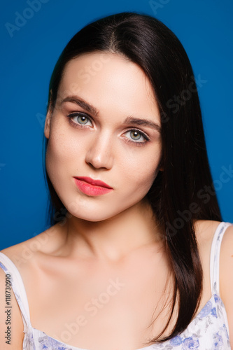 beautiful young brunette woman on a blue background in the studi
