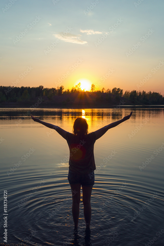 Silhouette of a woman in the river at sunset background.