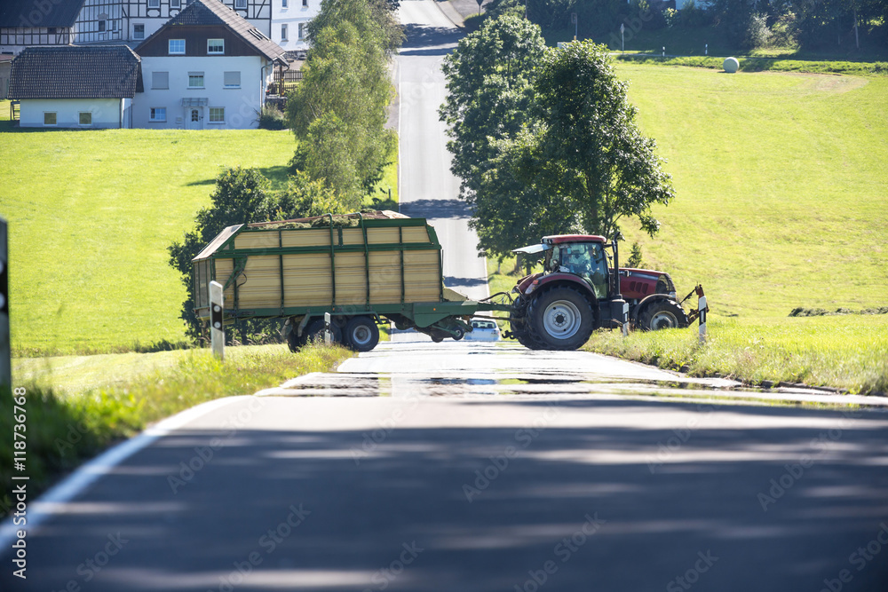 Naklejka premium tractor crossing a country road