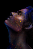 Glowing neon makeup with dramatic look in his eyes. Creative body art on the theme of space and stars. Amazing close-up portrait glow in the dark makeup.