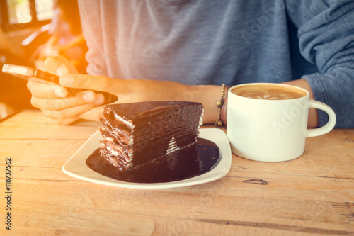 woman use mobile phone with coffee cup and chocolate cake on woo