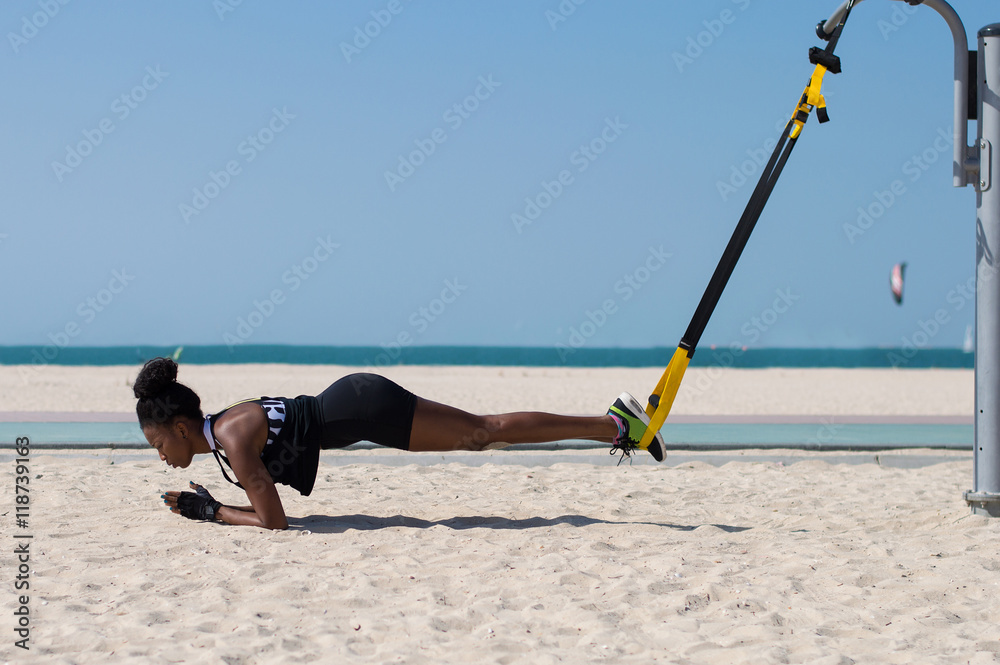 Female african doing difficult exercises using special ropes for