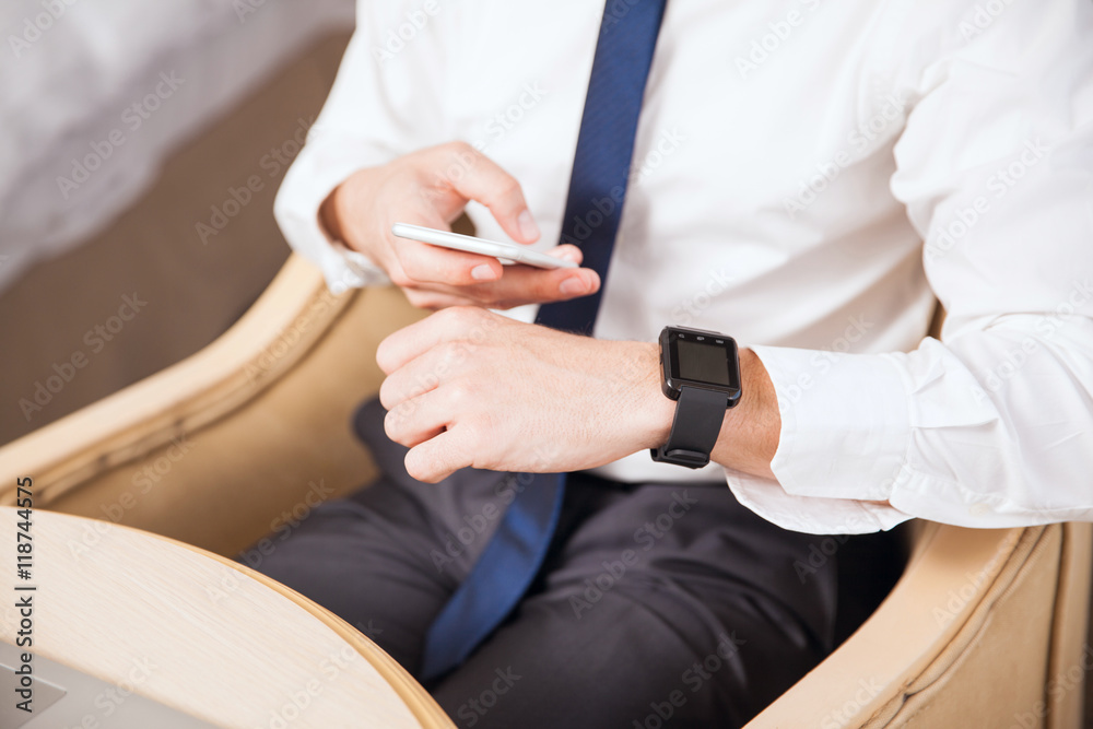 Fototapeta premium Businessman syncing smart watch to his phone