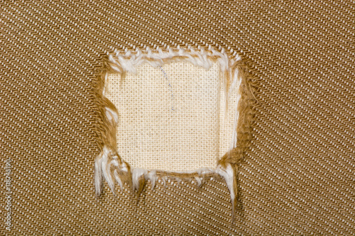 Square hole in fabric of sofa. Canvas like cotton material covering a brown settee unravelled into large square hole photo