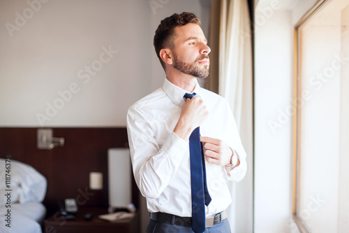 Valokuva Businessman fixing his tie in a hotel room