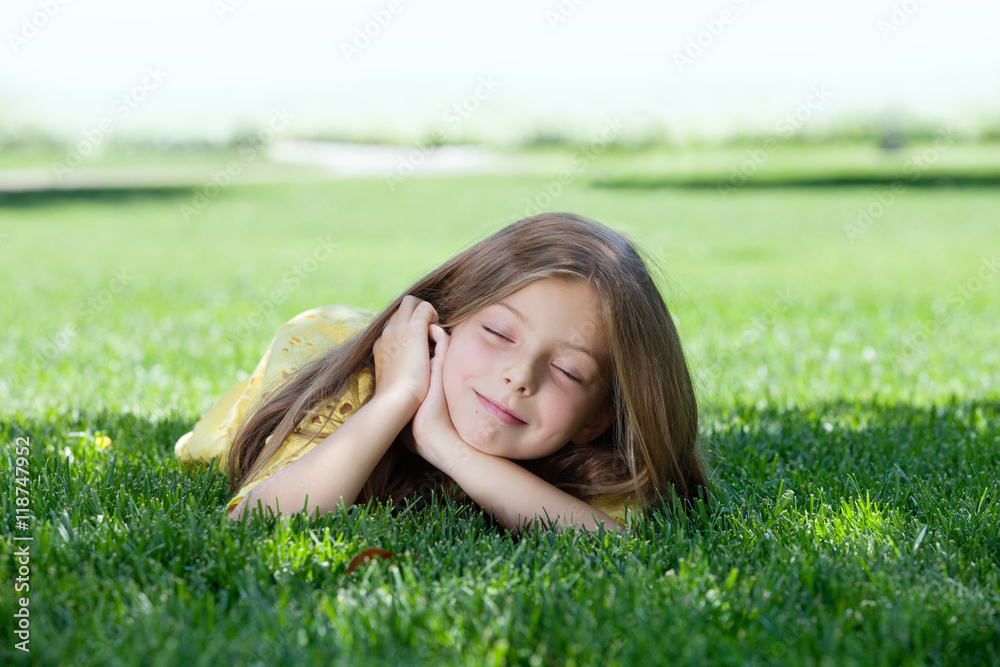 portrait of little girl laying on the grass in summer environment portrait of little girl laying on the grass in summer environment