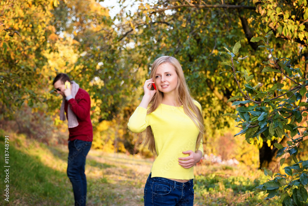 Young couple using a mobile phones. Young couple talking themselves by mobile phone. Young couple using a mobile phones. Young couple talking themselves by mobile phone.