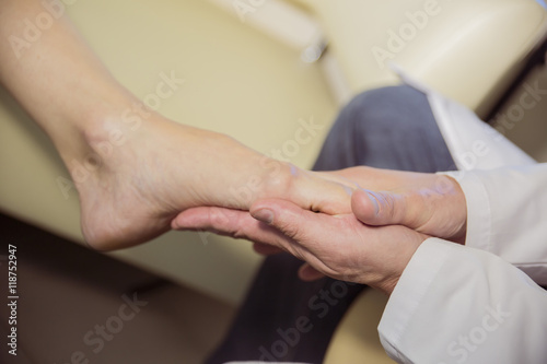the hands of the doctor examines the foot of a patient