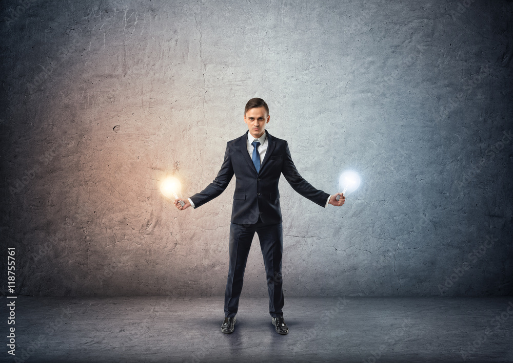 Fototapeta premium Front view of a businessman standing and holding glowing light bulbs in both hands