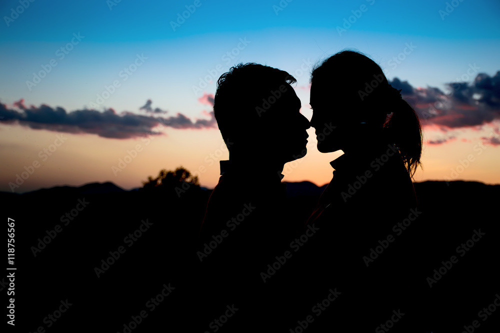 Silhouette couple kissing over sunset