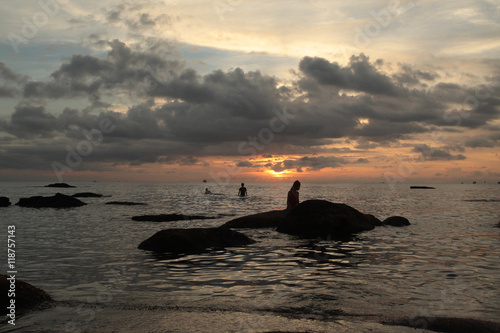 beautiful cloudy sunset over the ocean with people silhouettes photo