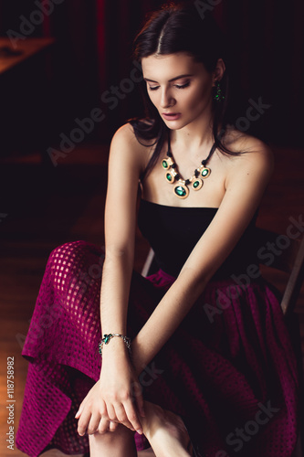 woman in green jewelry sitting on chair looking down