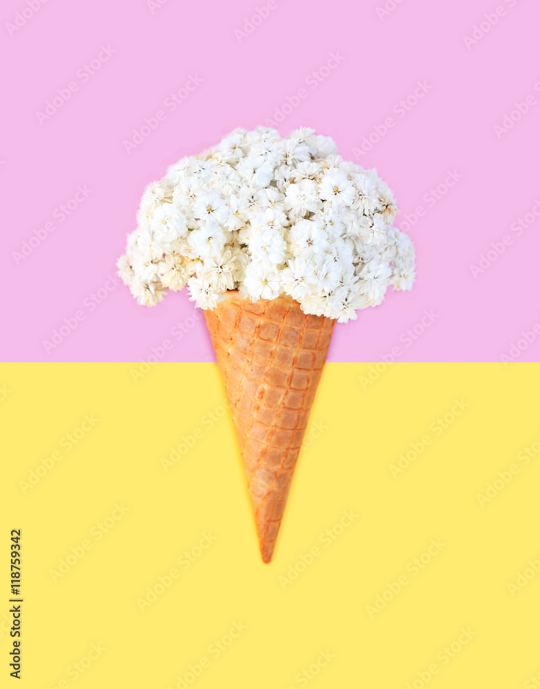 Ice cream cone with flowers over pink yellow background top view Ice cream cone with flowers over pink yellow background top view