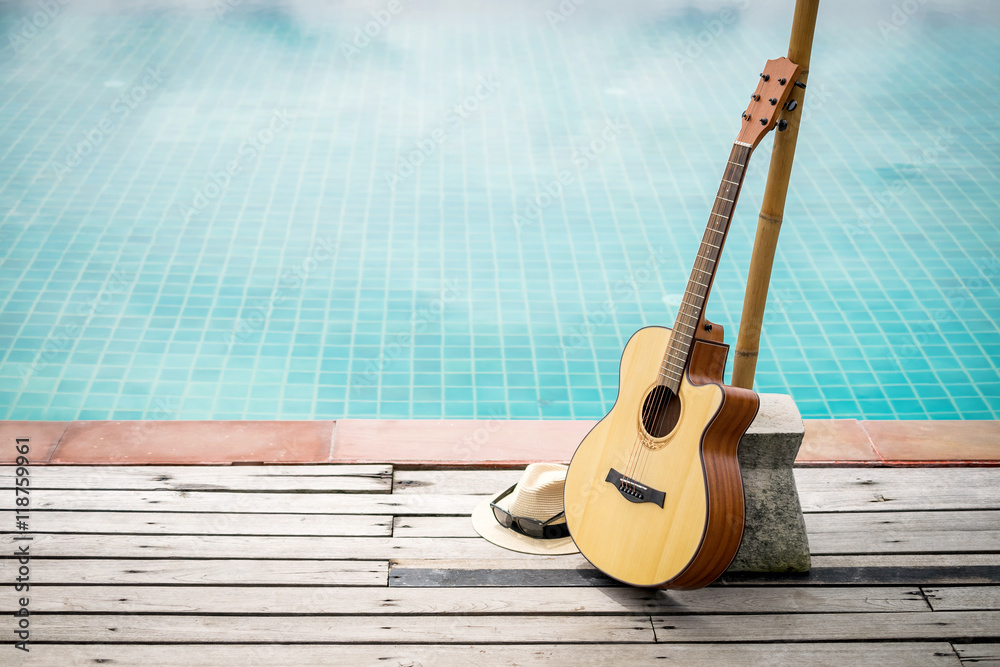 Obraz premium Acoustic guitar leaning on swiming pool.