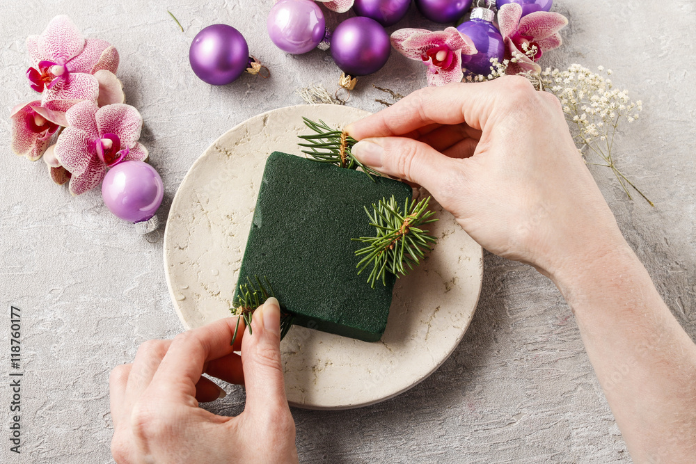 Φωτογραφία Woman making christmas decorations with violet balls, fir and or