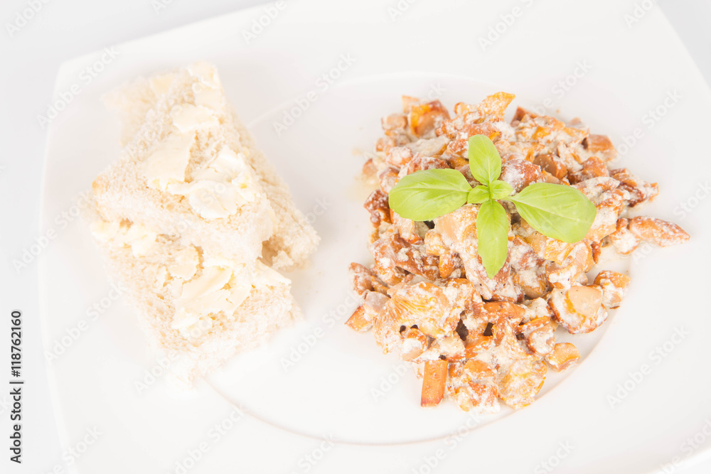 Sauteed chanterelle with cream and garlic and some white bread on a plate decorated with basil