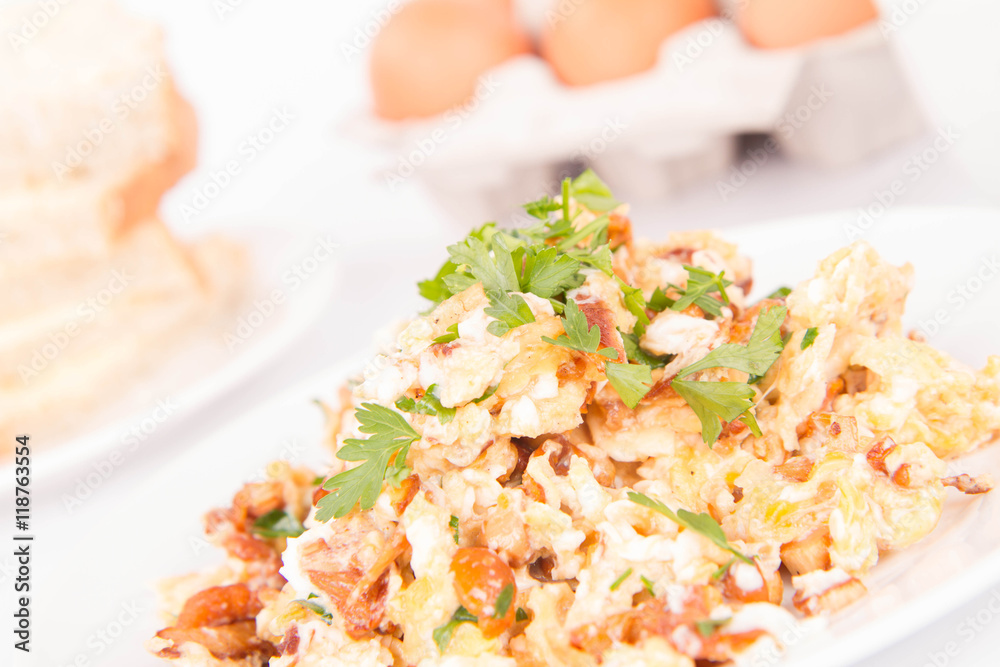 Scrambled eggs with chanterelle and parsley with some white bread on a white background Scrambled eggs with chanterelle and parsley with some white bread on a white background
