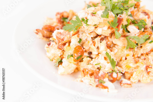Scrambled eggs with chanterelle and parsley with some white bread on a white background