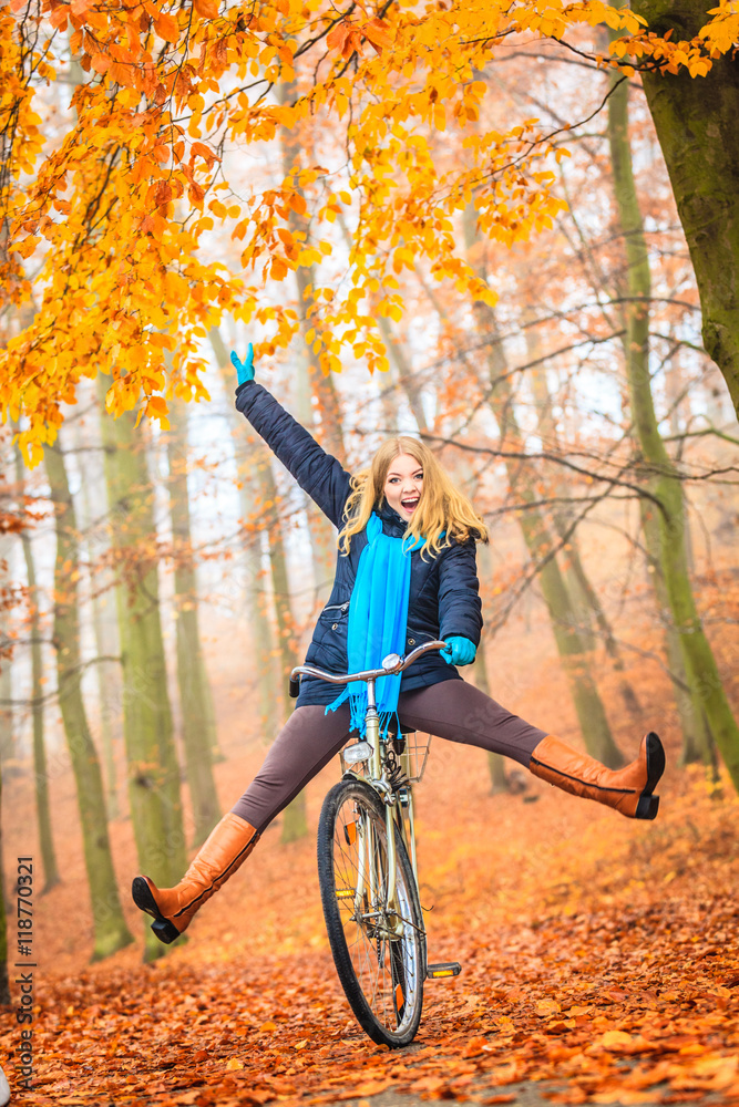 Fototapeta premium Active woman having fun riding bike in autumn park