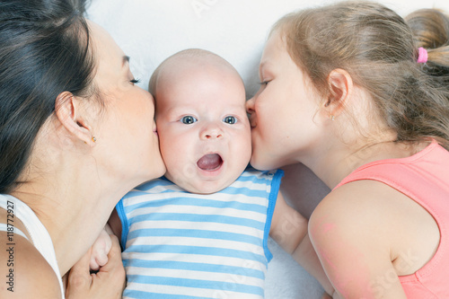Happy family mother with daughter kissing baby