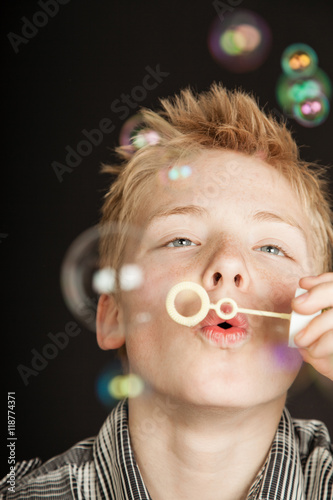Boy blowing bubbles through plastic wand