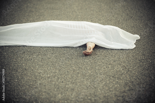 Dead body covered with sheet and hand sticking out