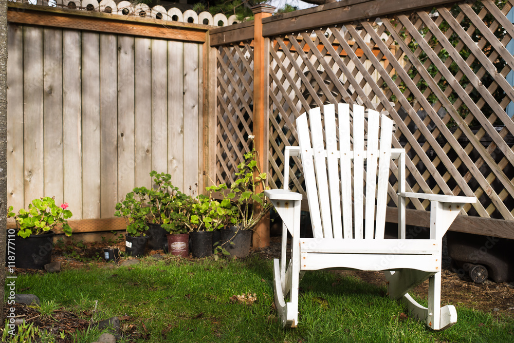 old, white, wood and empty adirondack chair in a cozy, private garden old, white, wood and empty adirondack chair in a cozy, private garden