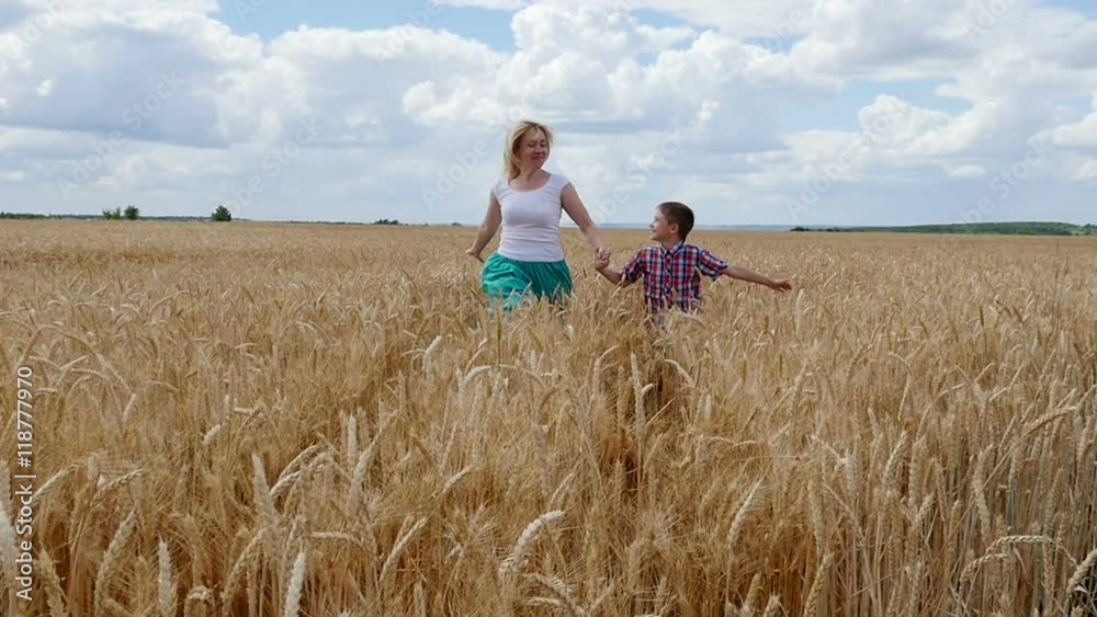 Mother and son running on the wheat field. Happy family in summer field Mother and son running on the wheat field. Happy family in summer field