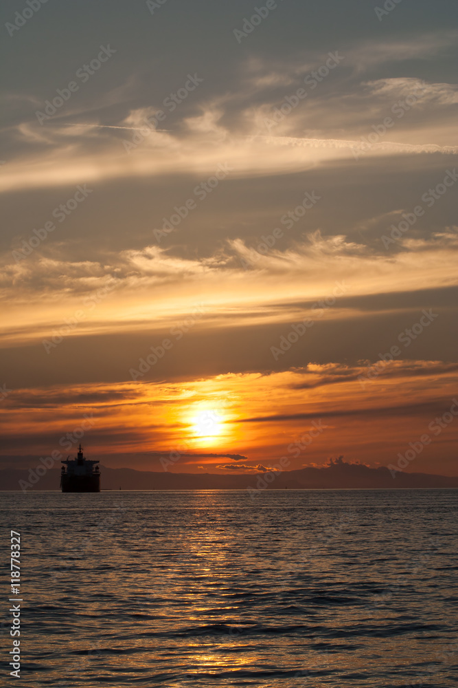 huge cargo ship at golden sunset, beautiful sky and clouds in English Bay, Vancouver, British Columbia, Canada huge cargo ship at golden sunset, beautiful sky and clouds in English Bay, Vancouver, British Columbia, Canada