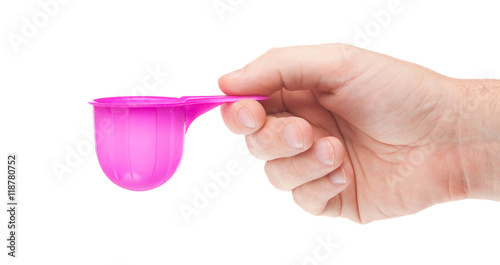 Washing powder in measuring cup in human hand on white background