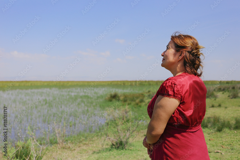 Happy old woman in wild flower field and sky.
