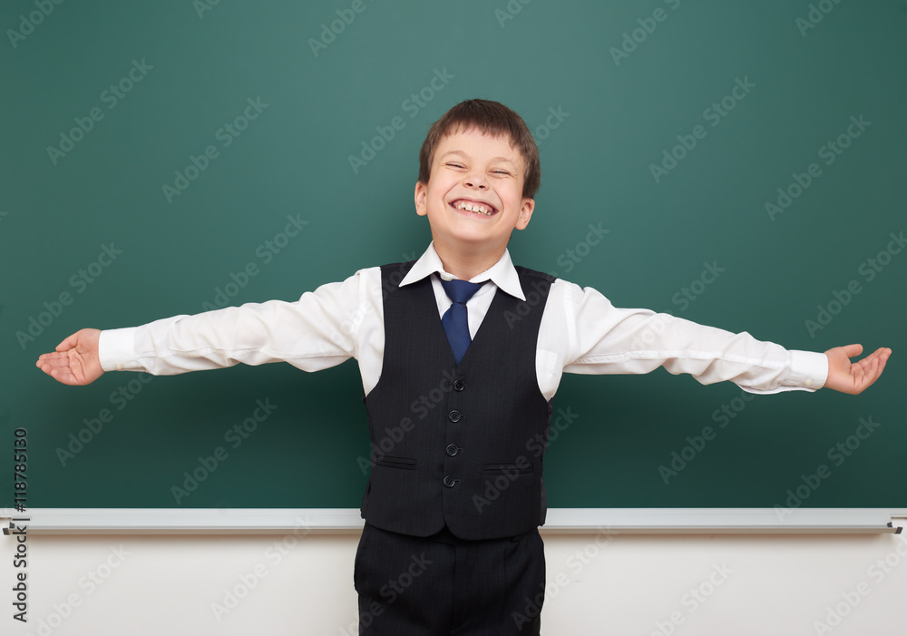 school student boy posing at the clean blackboard and open arms, grimacing and emotions, dressed in a black suit, education concept, studio photo school student boy posing at the clean blackboard and open arms, grimacing and emotions, dressed in a black suit, education concept, studio photo