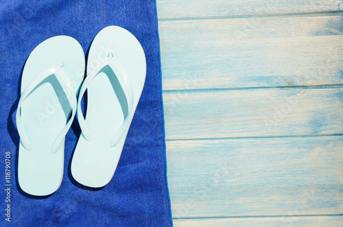 flip flops and towel on blue wooden table with sunlight