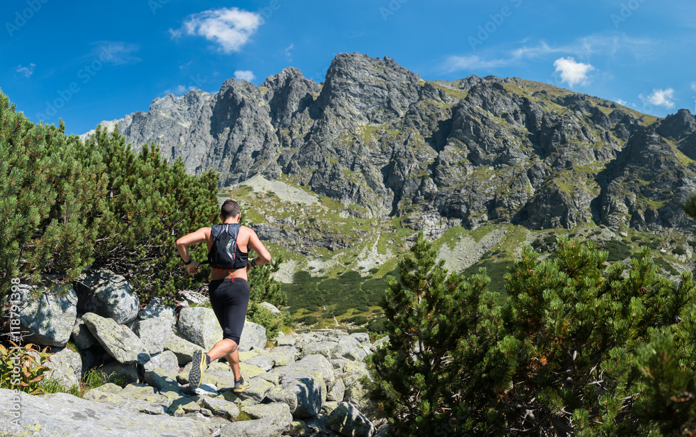 young man without tshirt running with backpack ultra trail race in high mountains with peak view