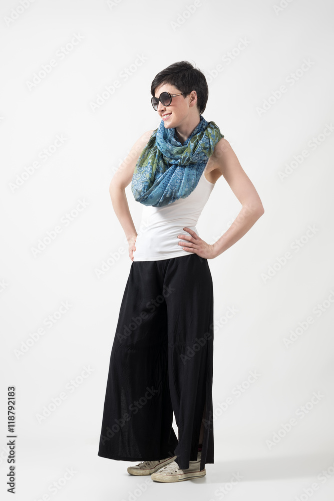 Short hair girl with sunglasses and shawl posing with hands on hips over gray studio background. Short hair girl with sunglasses and shawl posing with hands on hips over gray studio background.