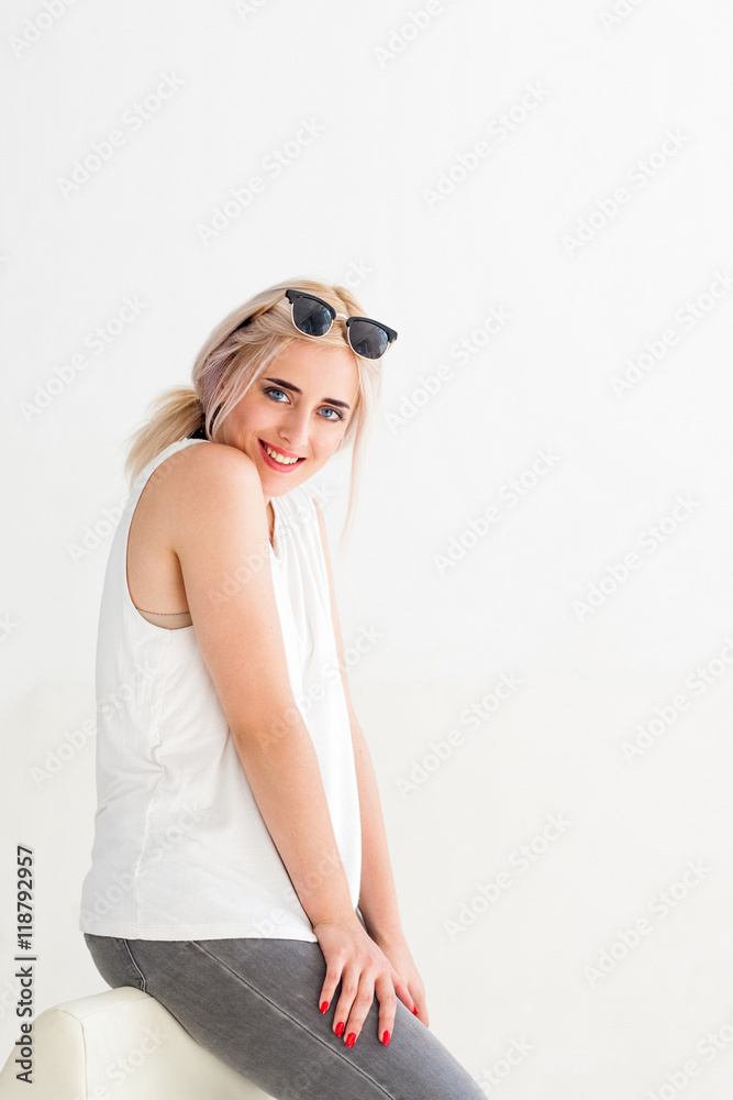 Cheerful blonde model smiling at camera while sitting, white background. Beauty portrait, perfect makeup. Sexy fashion woman Cheerful blonde model smiling at camera while sitting, white background. Beauty portrait, perfect makeup. Sexy fashion woman