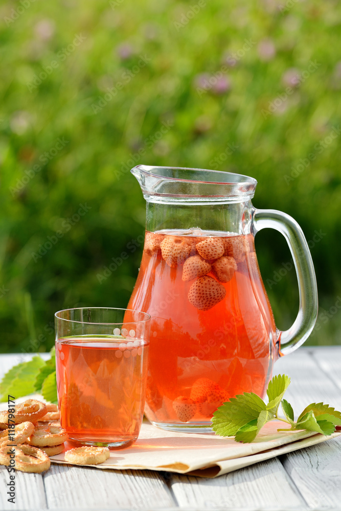 Homemade strawberry compote in glass decanter with pretzels on white wooden table in garden Homemade strawberry compote in glass decanter with pretzels on white wooden table in garden