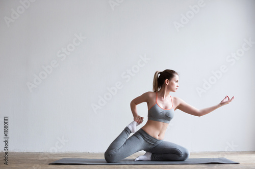 Young woman doing yoga exercise on mat.