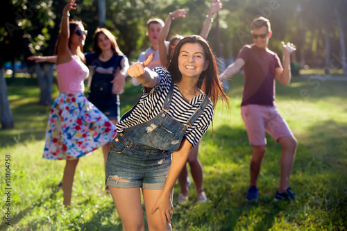 summer holidays and teenage concept - young girl out with friends outside. Portrait of a young girl and his friends in the background.