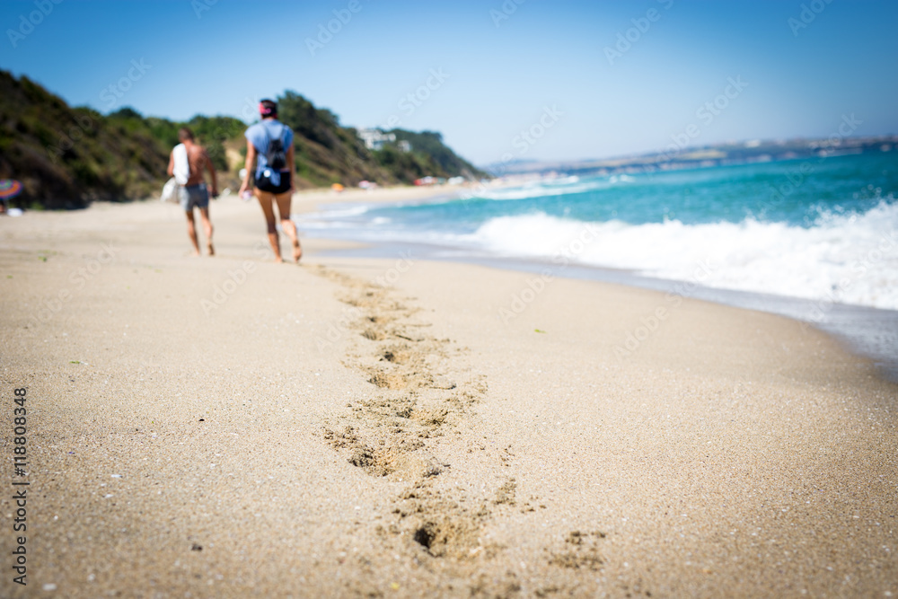 Footprints in sand - walking along the beach, vacation background
